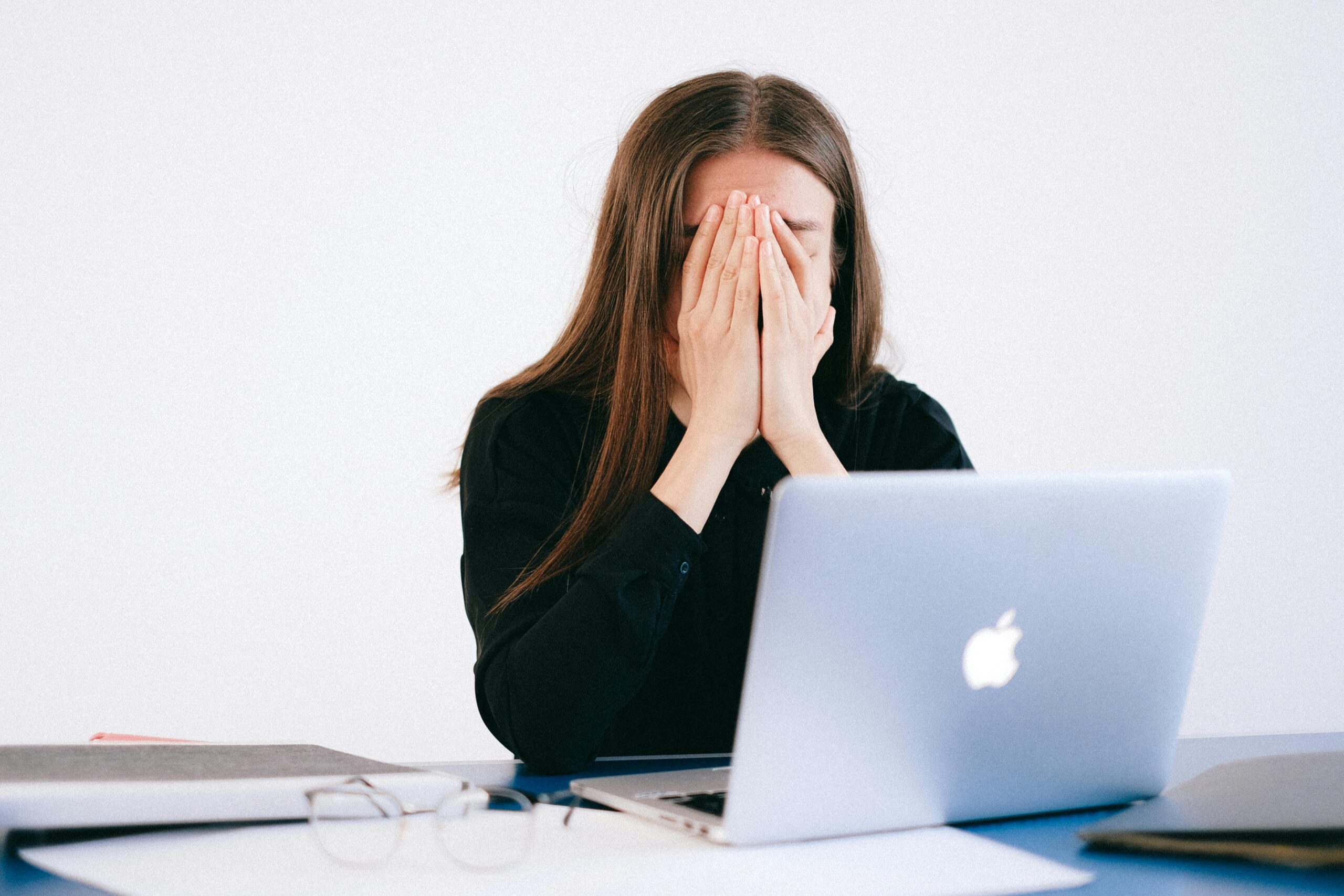 Powrót do formy po urlopie. Woman feeling stressed and overwhelmed at her desk while working remotely on a laptop.