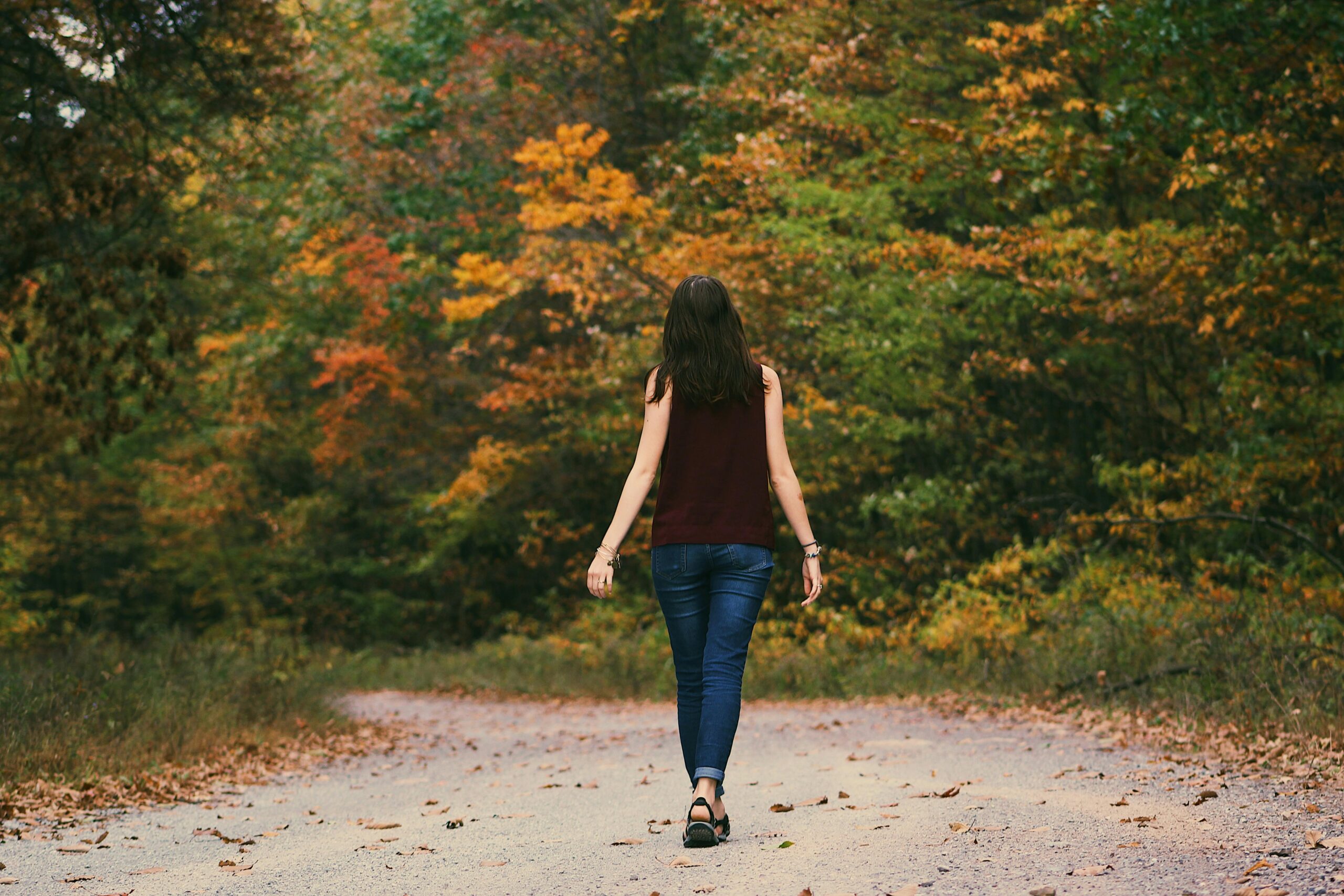 jak przygotować organizm do zbliżającej się jesieni A young woman walks down a colorful autumn forest path, surrounded by vibrant leaves.