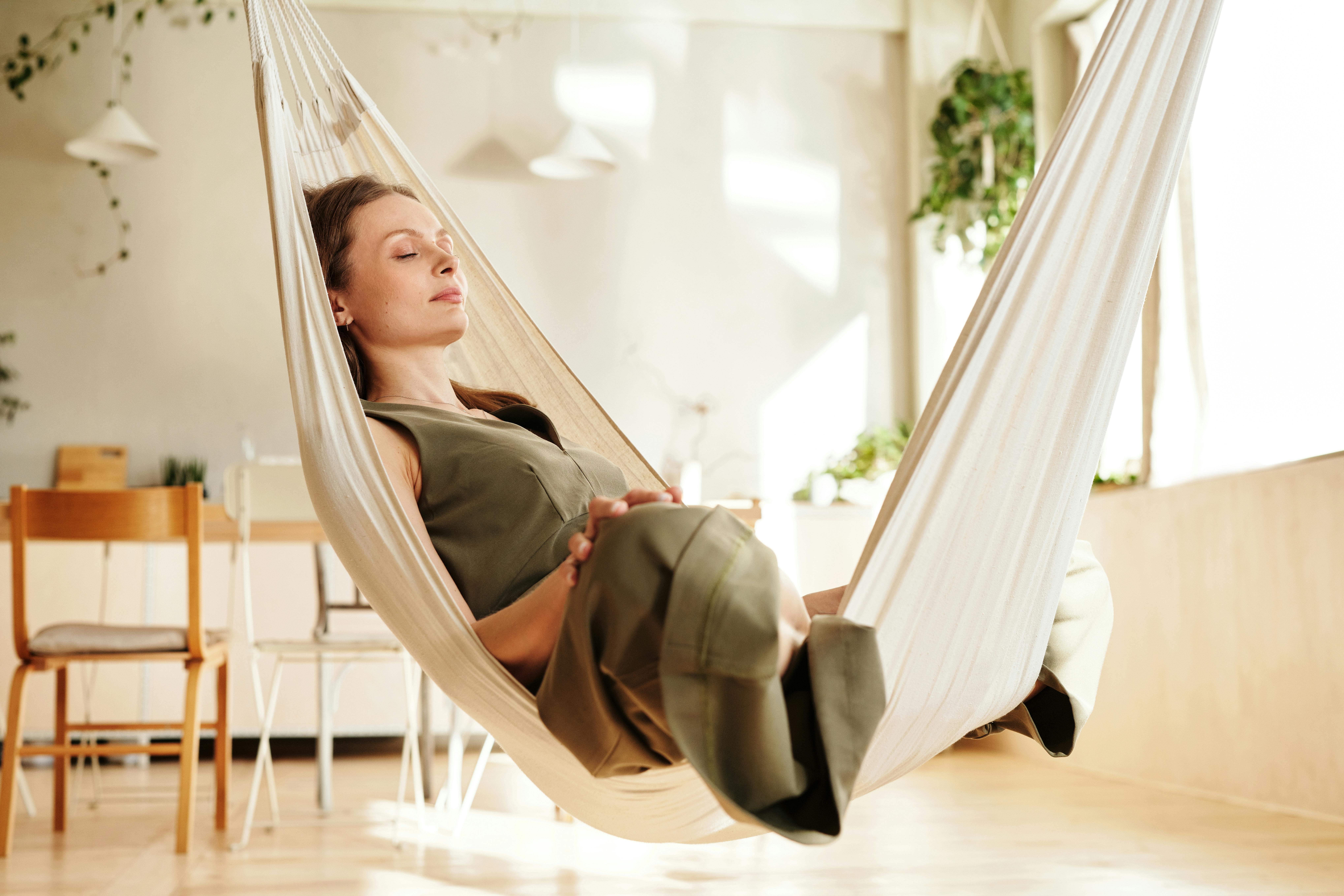 Glicynian magnezu A woman enjoys a peaceful nap on an indoor hammock under soft natural light.